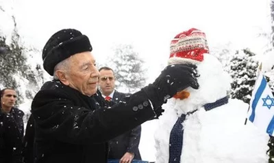 Президент Шимон Перес лепит снеговика.