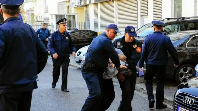 Черногорские полицейские ведут задержанного по улице. Фото ВВС