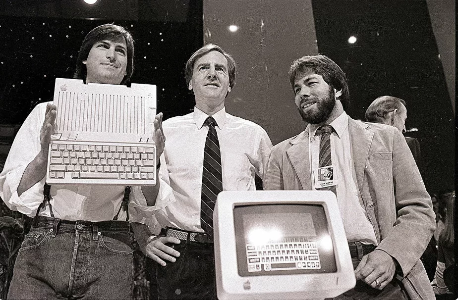 Слева направо: Стив Джобс, Джон Скалли и Стив Возняк во время презентации нового компьютера компании Apple II в Сан-Франциско, США. 24 апреля 1984 года