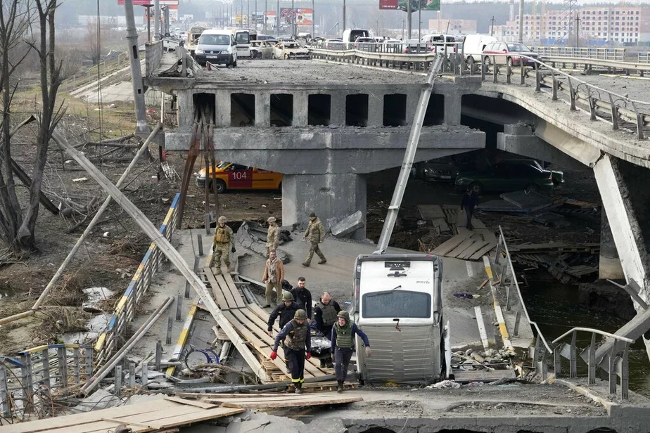 Украинские солдаты несут по разрушенному мосту в Ирпени тело мирного гражданина, убитого российскими войсками, 31 марта. Фото: АР