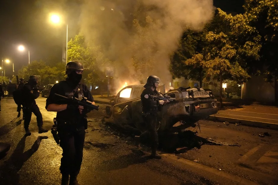 Полицейские проходят мимо сожженных автомобилей во время столкновений с молодежью в Нантере, 29 июня 2023 г. Фото: Christophe Ena / AP Photo